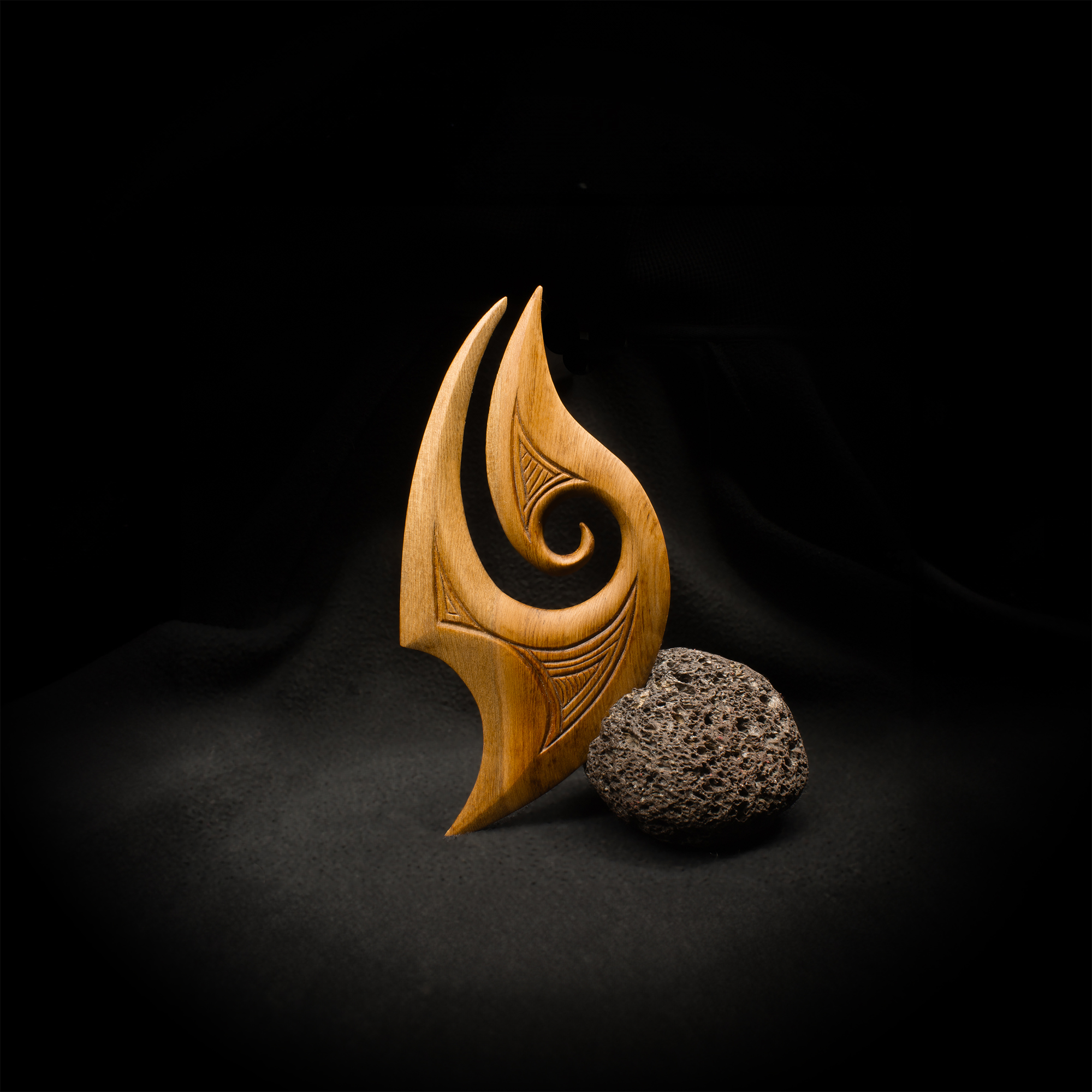 Artwork: Hei Matau, a fish hook shaped carving with a stone.